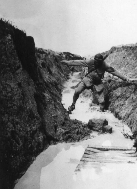 A runner attempts to pass a flooded trench. 