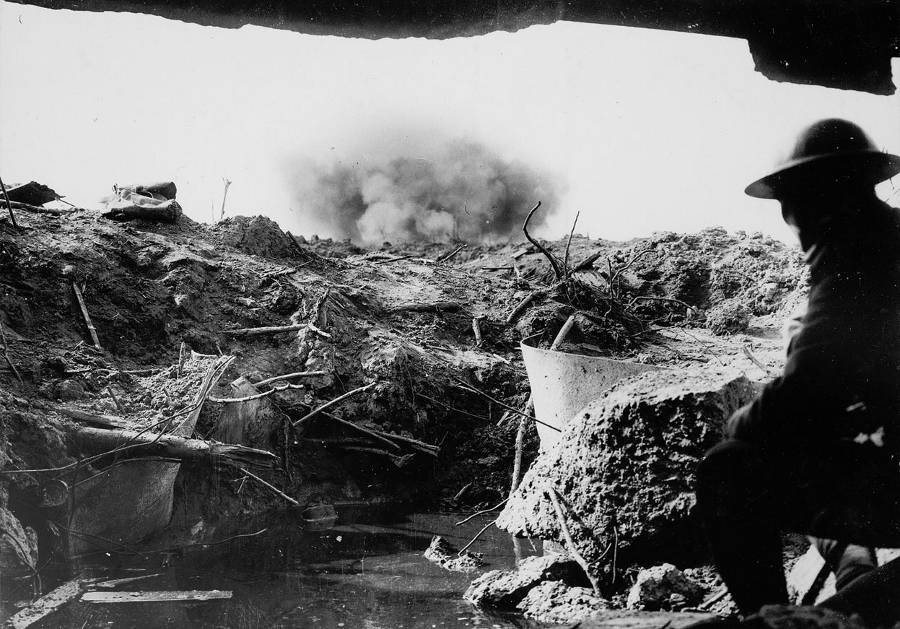 A shell explodes nearby this British soldier sheltering in a dugout.