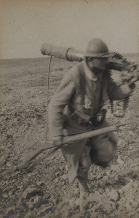 A French soldier carries back a captured German machine-gun during an assault.