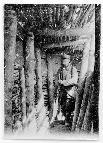 A soldier stands inside a covered trench, 1915.