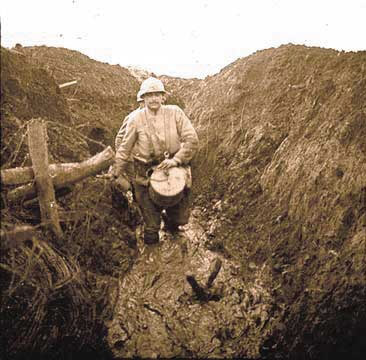 A soldier carries a drum through the muddy communication trenches at Les Éparges, 1915.
