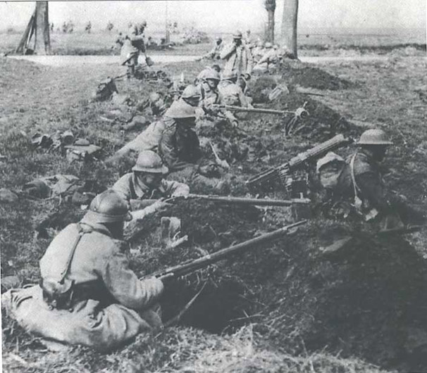 A mixed force of British and French soldiers sits in freshly dug fox-holes, Somme, 1918.