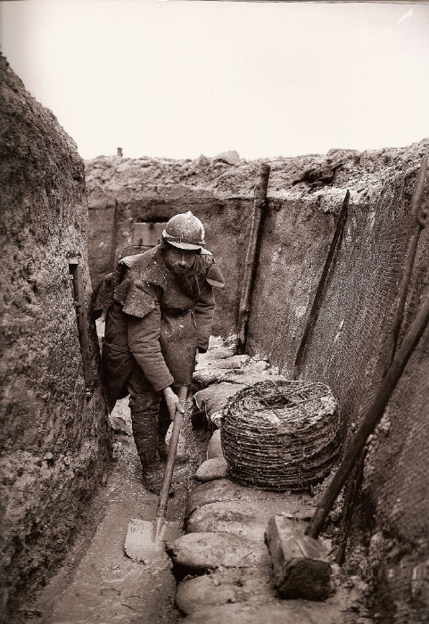 An engineer shovels mud out of a trench, Nieuport 1915.