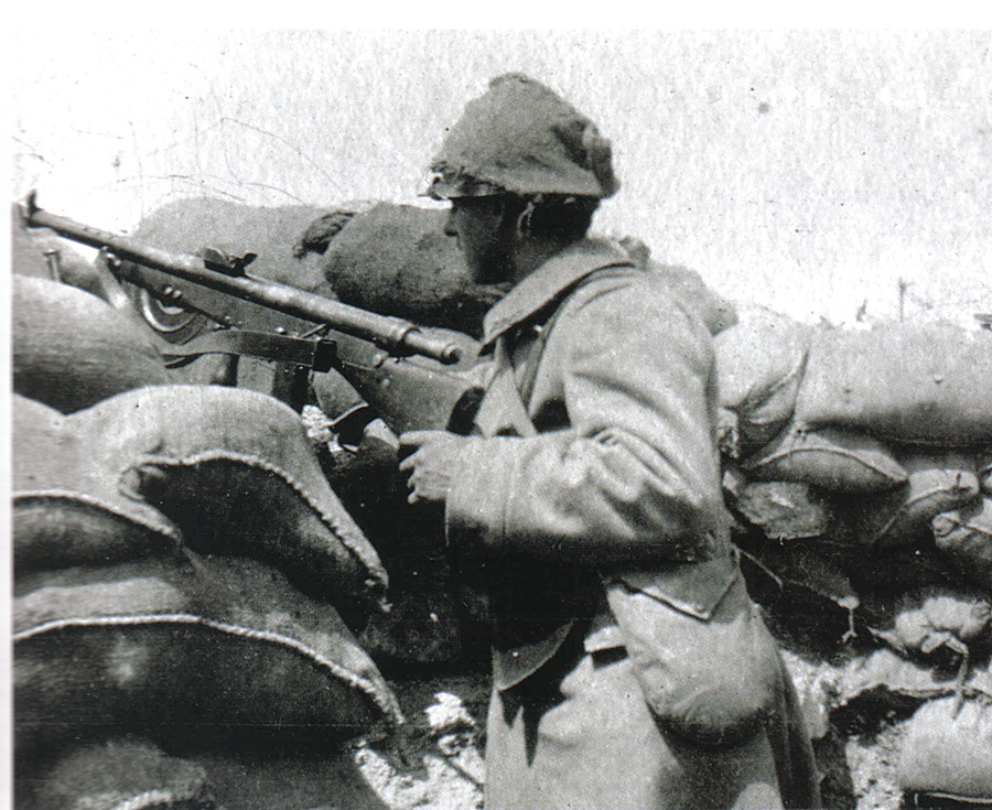 A Chauchat gunner has improvised camouflage for his helmet using a sandbag.
