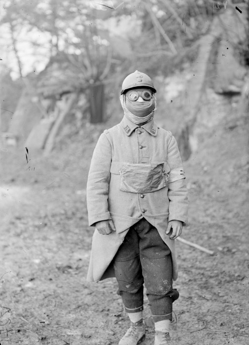 An anonymous soldier dons a P2 gas mask and goggles. (1915)