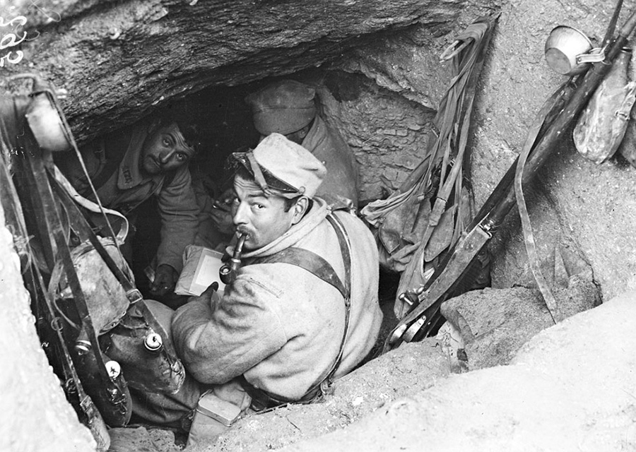 A soldier reads a letter at the entrance to an underground shelter in Champagne.