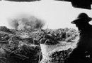 A shell explodes nearby this British soldier sheltering in a dugout.