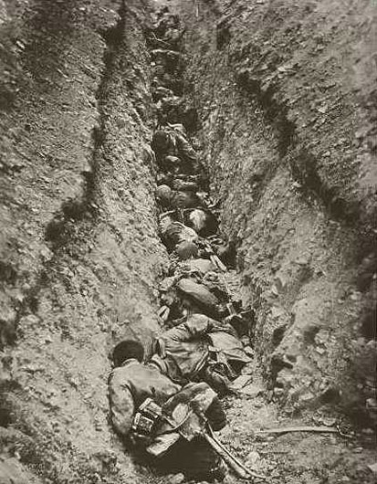 German troops caught by an enfilading machine-gun fire lay piled up in a communication trench.