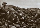 French soldier in the remains of a trench, huddling among piles of German dead. 